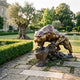 Monumental Traditional Prowling Panther Bronze Sculpture by Giant Sculptures in warm golden-brown patina, crouched on a rocky base on a stone garden path.