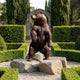 Monumental Traditional Rearing Grizzly Bear Bronze Sculpture by Giant Sculptures, 300cm tall, displayed on rough stone boulders in a formal hedged garden.