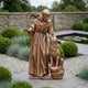 Monumental Traditional Robed Friar with Dove and Wolf Bronze Sculpture by Giant Sculptures, 210cm, displayed in a walled garden beside a lily pond.