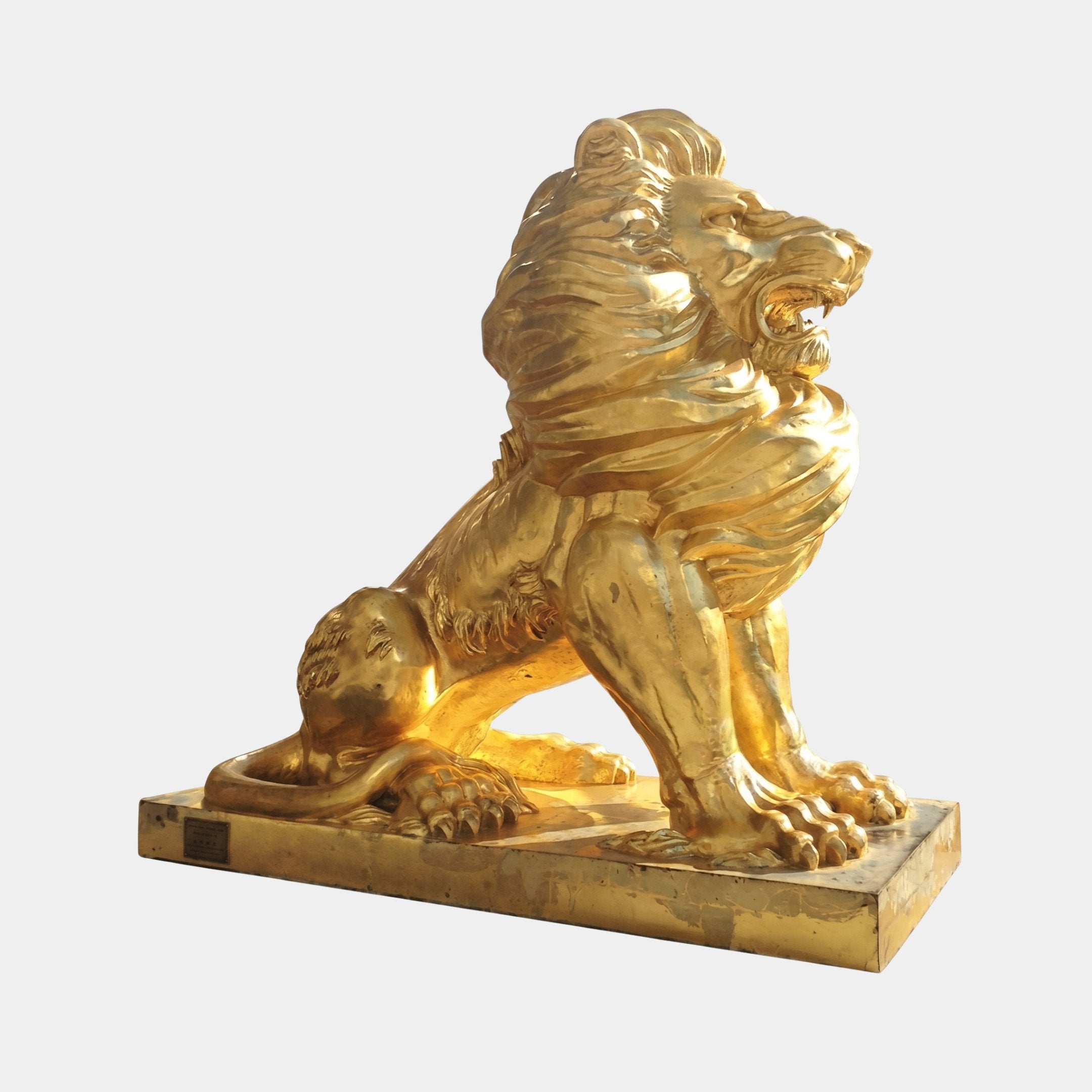 Monumental Traditional Seated Roaring Lion Bronze Sculpture in polished gold finish by Giant Sculptures, side view on rectangular base against light grey.