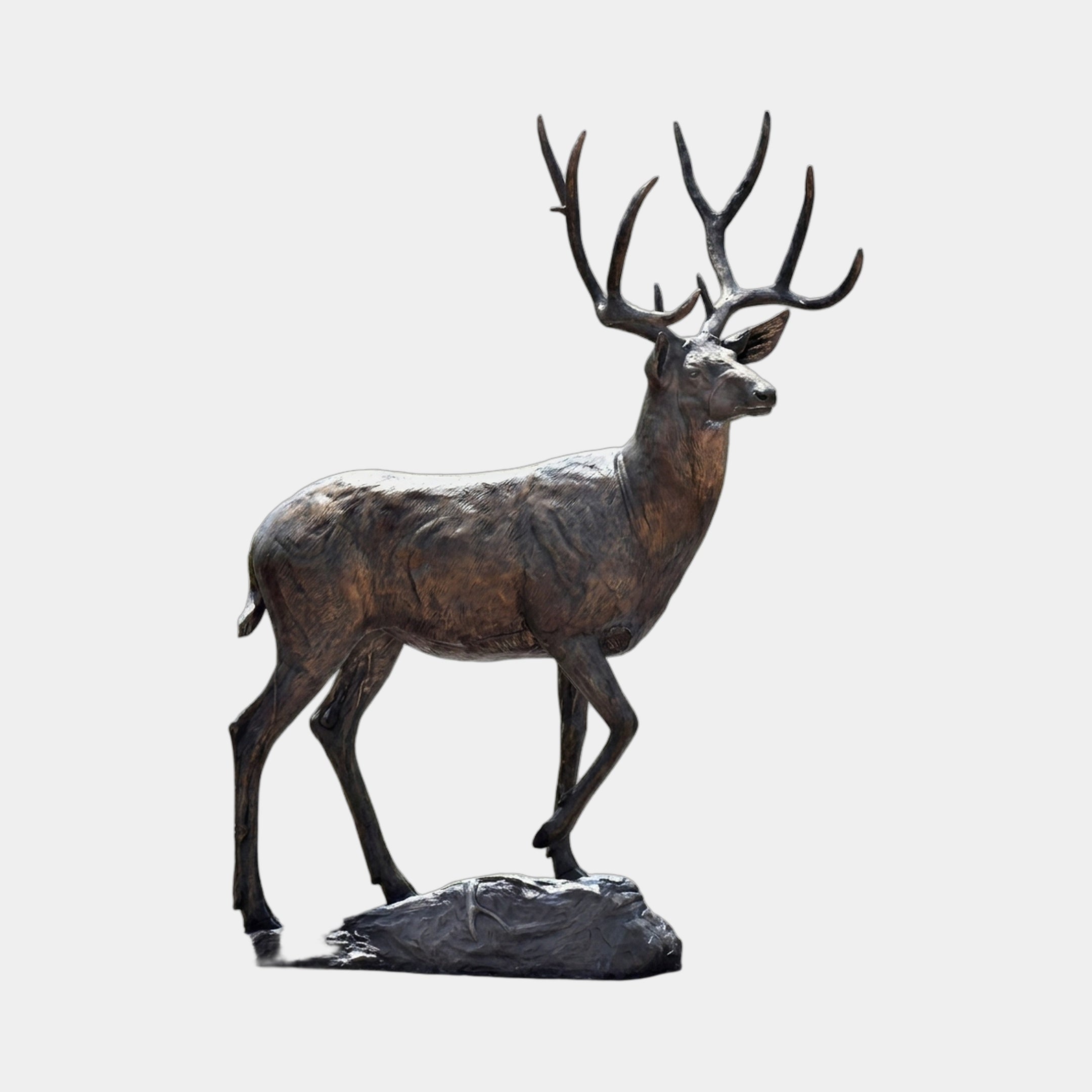 Monumental Traditional Walking Stag Bronze Sculpture by Giant Sculptures shown in side profile with multi-point antlers, dark brown patina, on a rocky base.