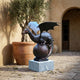 Giant Sculptures Monumental Winged Dragon on Orb Bronze Sculpture 180cm on a grey granite plinth in a sunlit courtyard beside a potted olive tree.