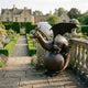 Monumental Traditional Winged Dragon on Orb Bronze Sculpture by Giant Sculptures, wings spread atop a sphere, on a manor garden terrace path.
