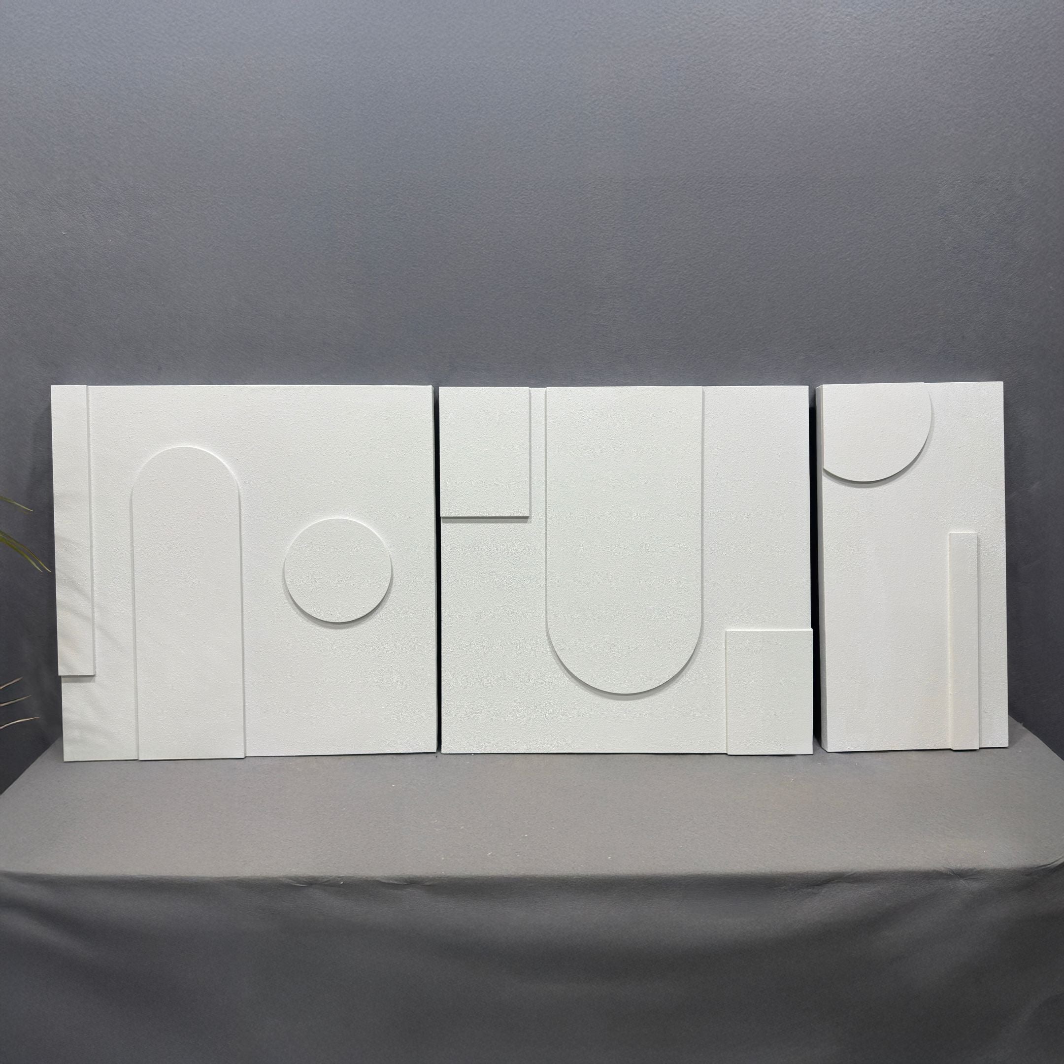The Moro III Triptych White Relief 3D Wall Art by Giant Sculptures features three white panels with geometric shapes in arcs, circles, and rectangles, creating striking contemporary decor when displayed side by side.
