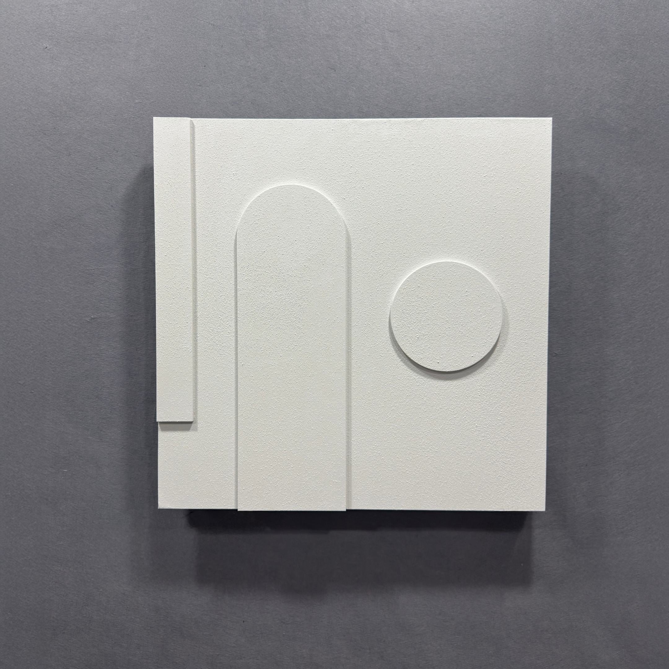 The Moro III Triptych White Relief 3D Wall Art by Giant Sculptures features a white minimalist square base with raised geometric forms—rectangle, arch, and circle—creating striking modern decor on a gray wall.