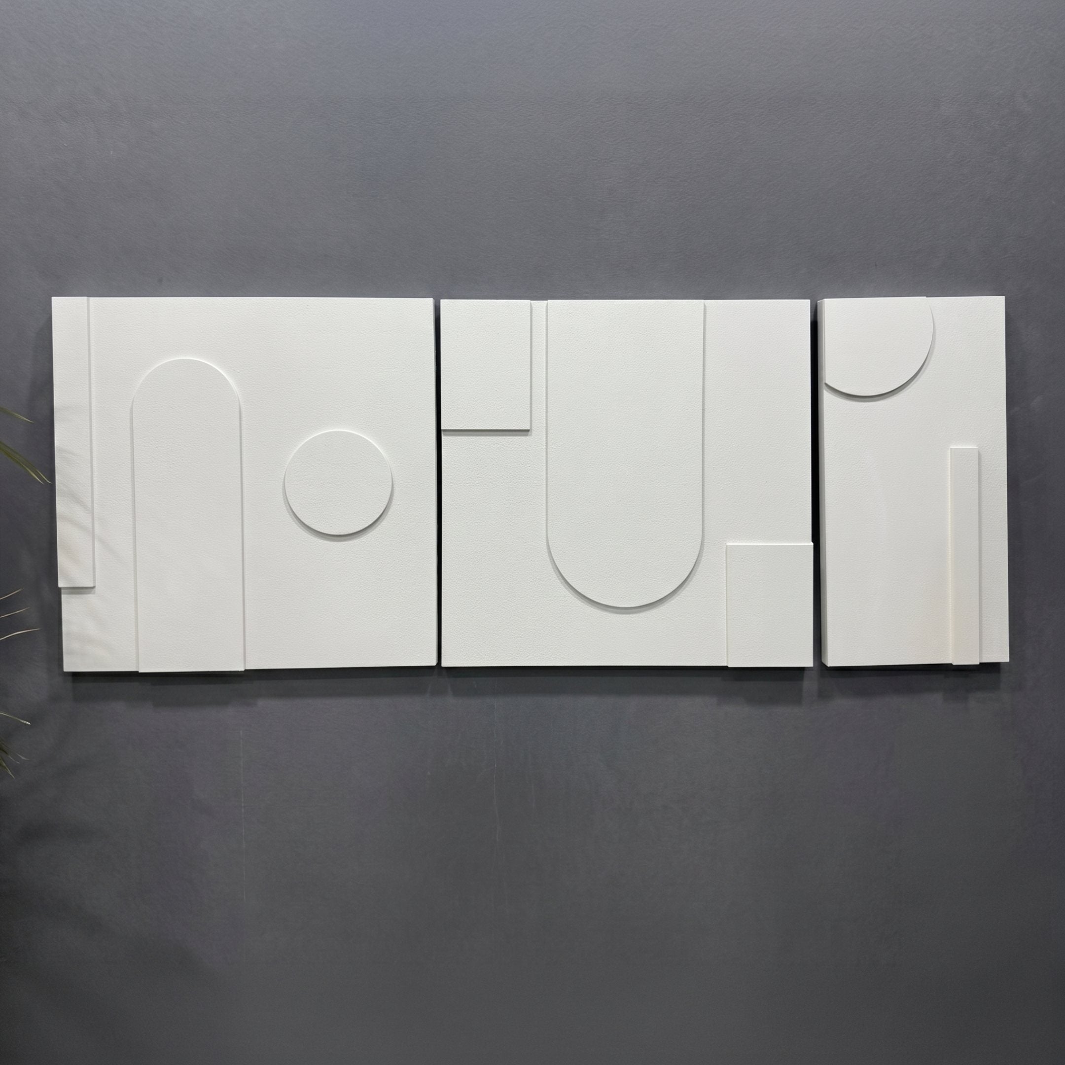 Moro III Triptych White Relief 3D Wall Art by Giant Sculptures, three matte white hand-painted sandstone panels with raised geometric arcs, circles, and linear forms mounted on a dark grey wall.