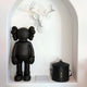 A 37cm Midnight Black Iconify resin figure by Giant Sculptures stands in a white alcove, with a modern white deer head sculpture above and a sleek black lidded container beside it.