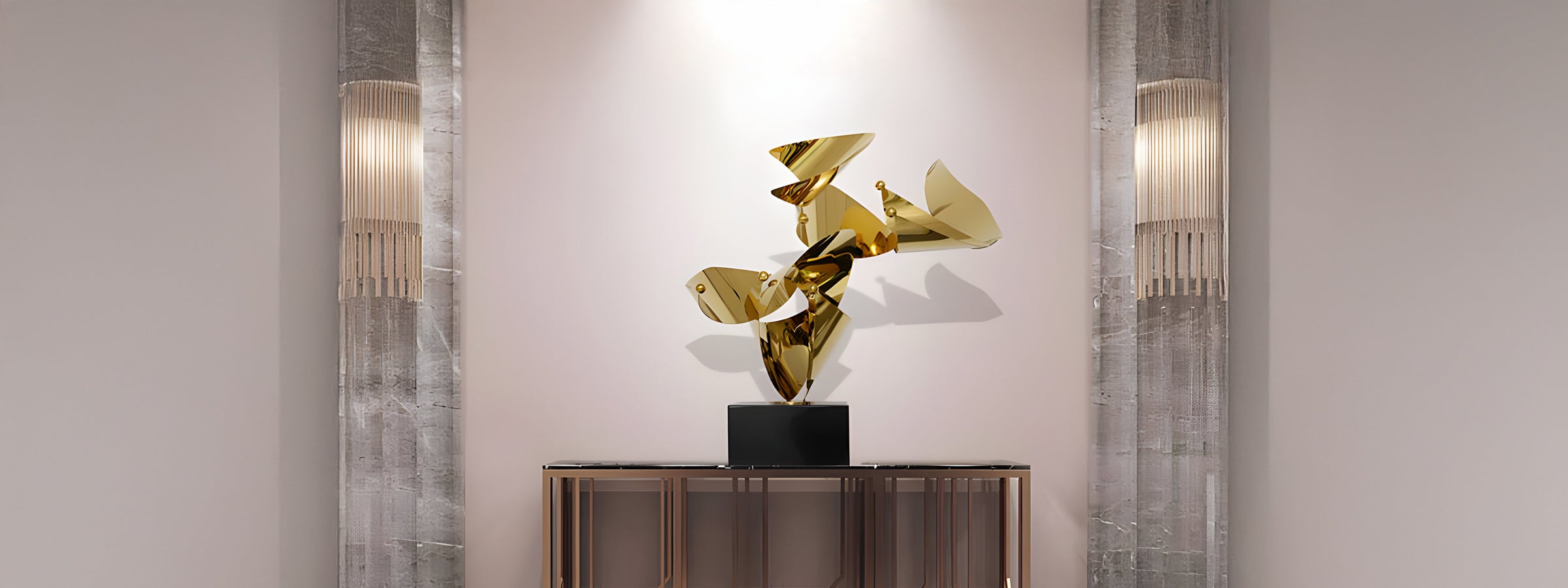 A modern art sculpture with gold metallic abstract shapes is displayed on a black pedestal. Its positioned against a light-colored wall between two stone columns with vertical light fixtures.