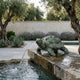 Small Traditional Tortoise Bronze Fountain by Giant Sculptures in verde antique patina, perched on a stone ledge spouting water into a pool in a Mediterranean garden.