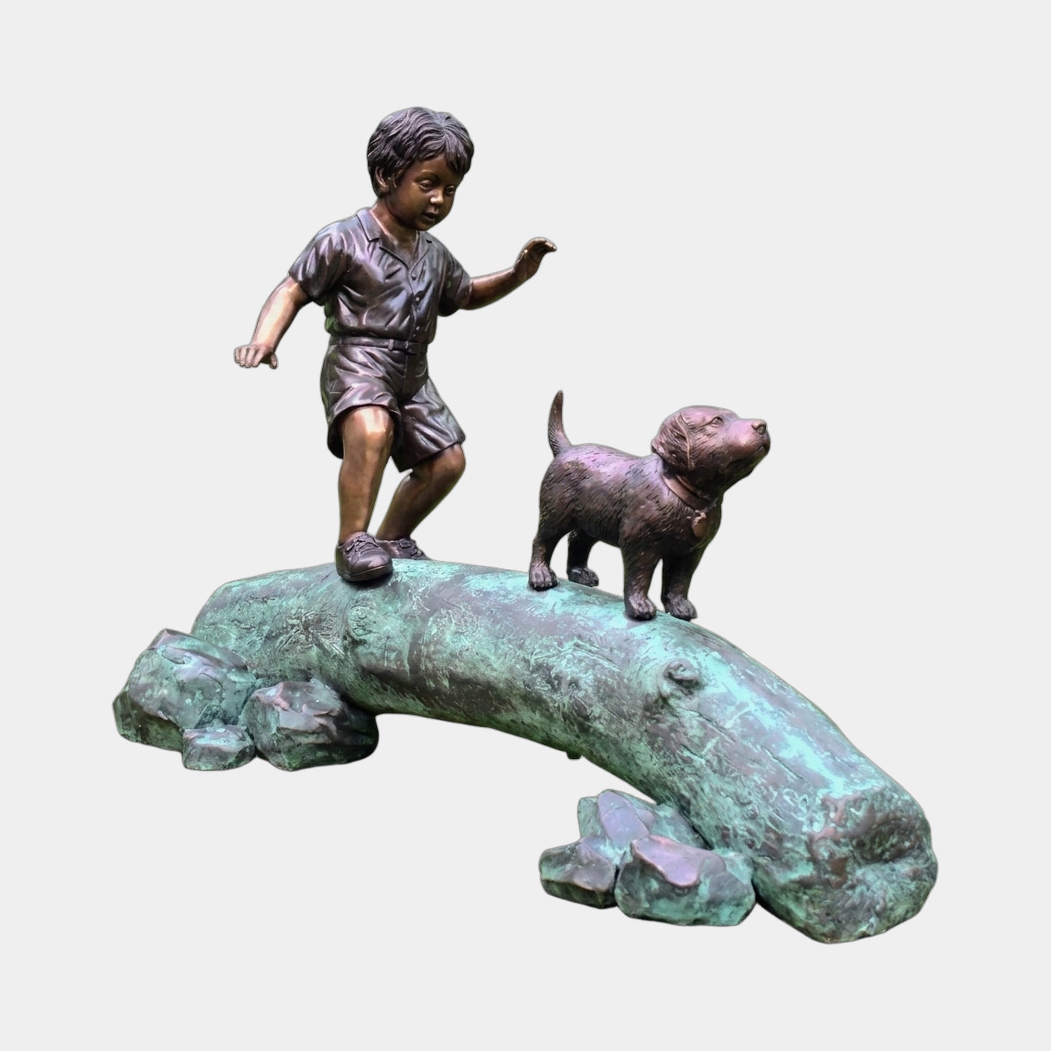 Traditional Boy and Dog Bronze Sculpture by Giant Sculptures showing a child mid-stride on a verdigris log with a small dog ahead, on plain background.