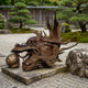 Traditional Chinese Dragon Head Bronze Sculpture by Giant Sculptures, shown in profile with flowing mane and pearl, displayed on a stone slab in a Japanese zen garden.
