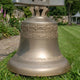 Traditional Church Bell Bronze Sculpture 100cm by Giant Sculptures, golden-brass finish with relief frieze and Latin inscription, displayed on a garden lawn.
