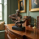 Traditional Cowboy Guitarist Bronze Bust by Giant Sculptures on a marble base, displayed on a wood sideboard beside leather books and antique portraits.