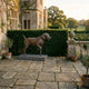 Traditional Labrador Retriever Dog Bronze Sculpture by Giant Sculptures in pointing stance on a grey plinth, set on a flagstone terrace beside a manor house.