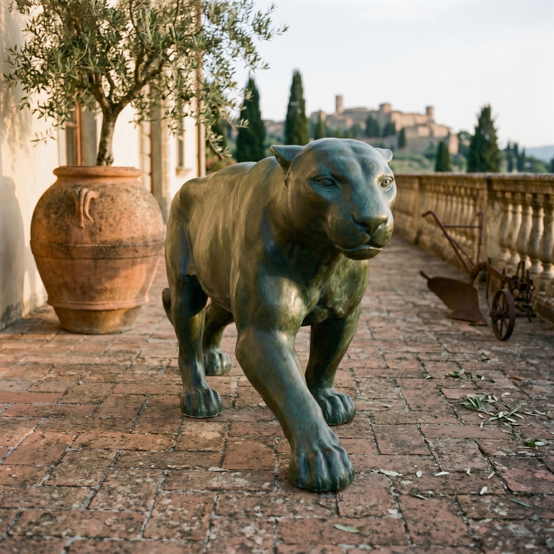 Traditional Prowling Panther Bronze Sculpture by Giant Sculptures in verdigris patina, stalking across a brick terrace with olive tree and Tuscan hilltop view.