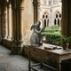 Traditional Rabbit with Lantern Bronze Sculpture by Giant Sculptures on a carved wooden table in a Gothic cloister, holding a lit candle lantern.
