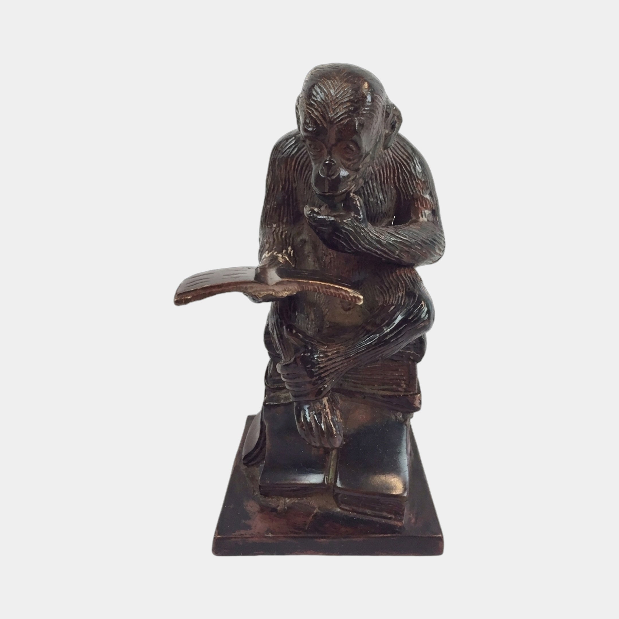 Traditional Reading Monkey Bronze Sculpture by Giant Sculptures, shown front-on with the chimpanzee hunched over an open book atop stacked volumes, on a plain background.
