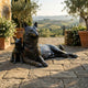 Traditional Reclining German Shepherd and Puppy Bronze Sculpture by Giant Sculptures on a Tuscan stone terrace with olive trees and rolling vineyard views.