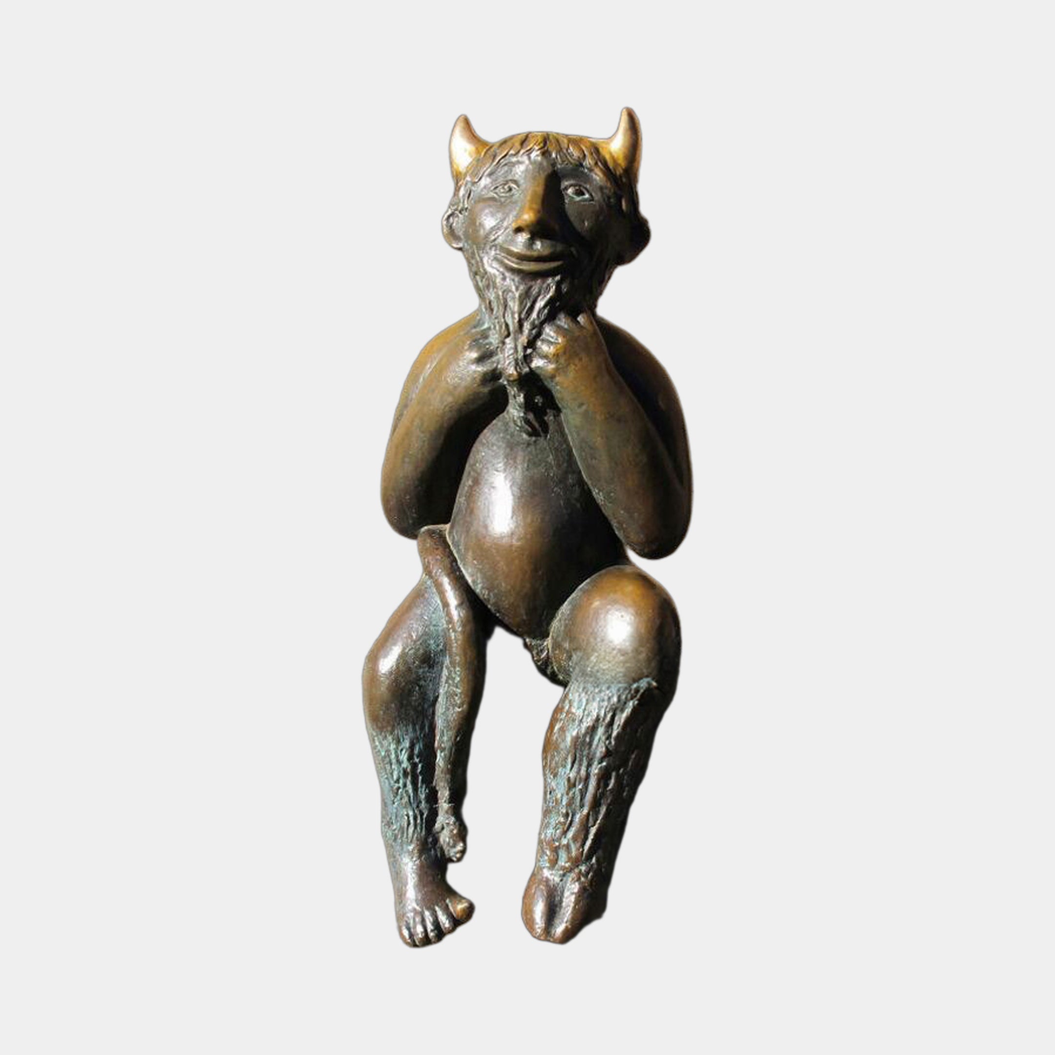 Traditional Seated Faun Bronze Sculpture by Giant Sculptures, shown front-on with gilded horns, braided beard, and verdigris goat legs against a plain background.