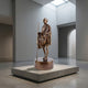Traditional Standing Gandhi Figure Bronze Statue by Giant Sculptures, 30cm, shown with staff on an inscribed cylindrical base atop a plinth in a gallery.